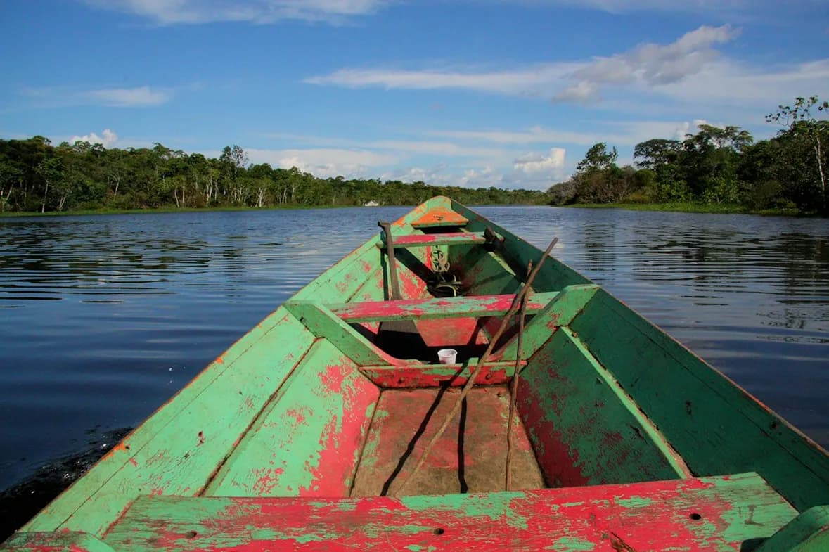 Proa de un bote de madera pintado navegando por un río amazónico